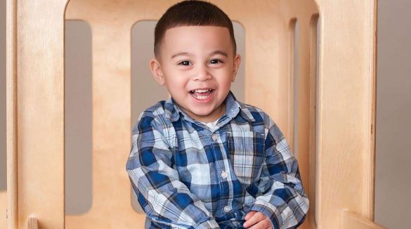 Little boy in plaid shirt sitting and smiling at camera