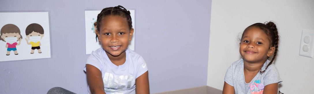 Two girls building puzzle cubes while smiling at the camera